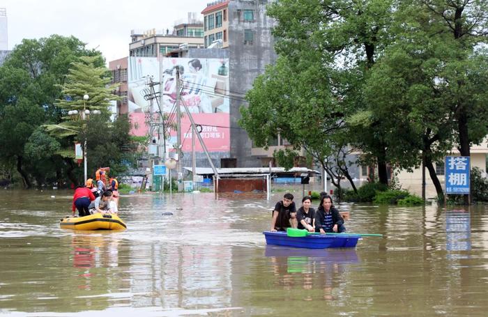 4月21日,广东清远英德市浛洸镇住户在积水的谈路上乘船出行。新华社记者 黄国保 摄